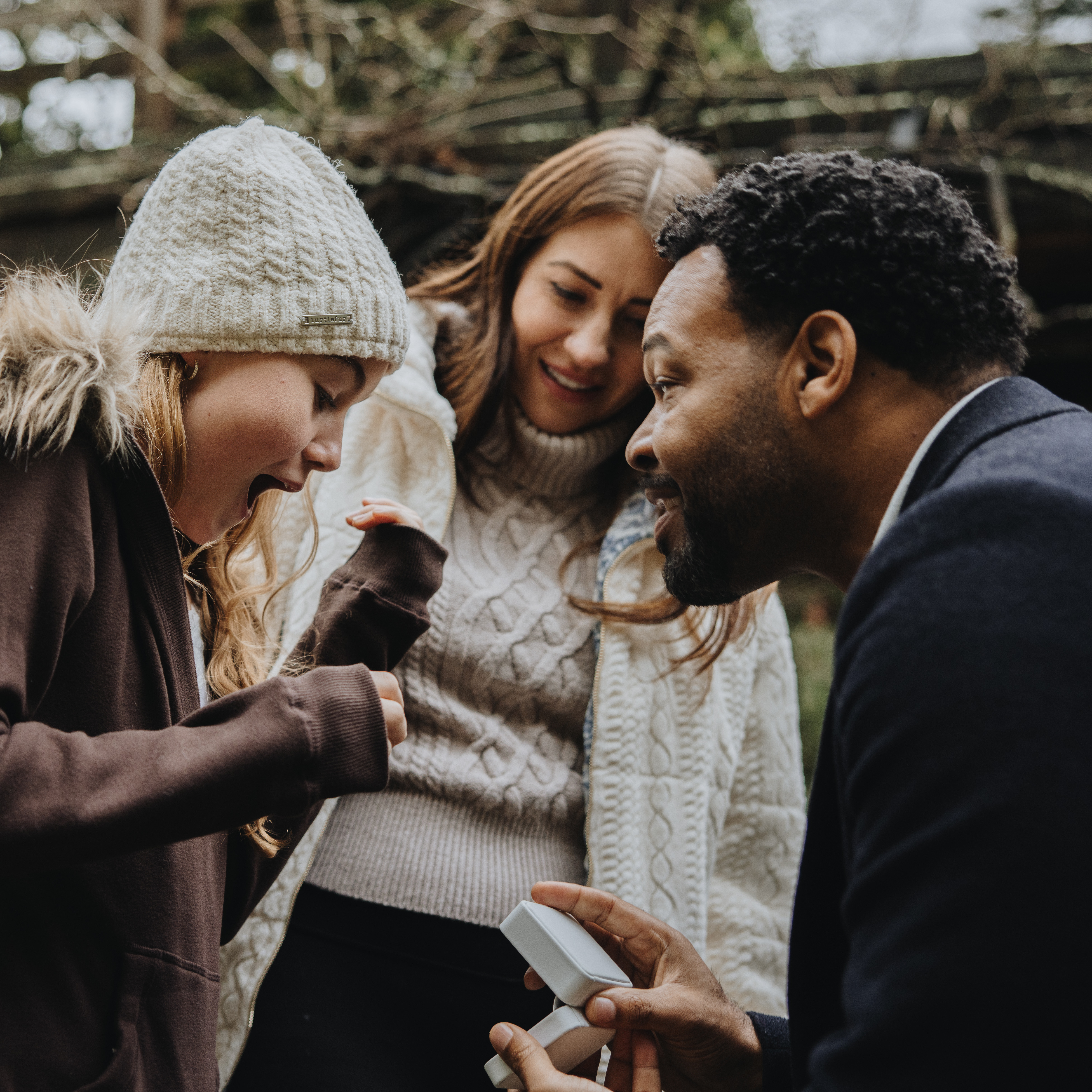 Emotional proposal moment showing a man proposing both to his partner and to her daughter with two rings