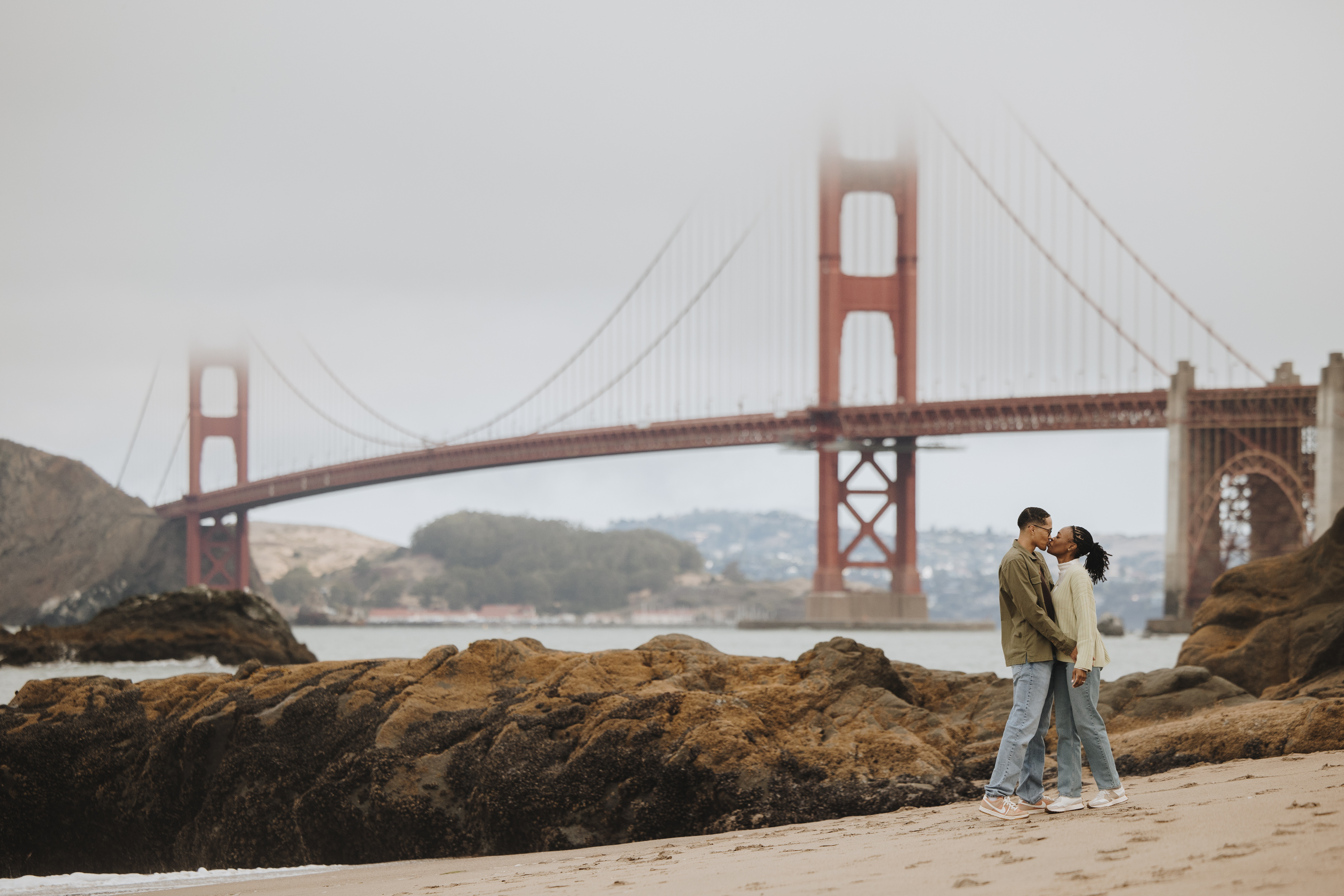 Proposal at Baker Beach near the rocks with the Golden Gate Bridge partially hidden by fog
